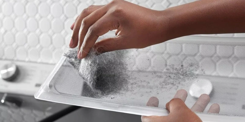 Hand removing lint buildup from dryer vent filter