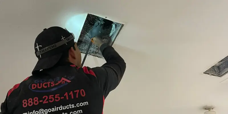 Ducts All Done technician cleaning ceiling air duct vent